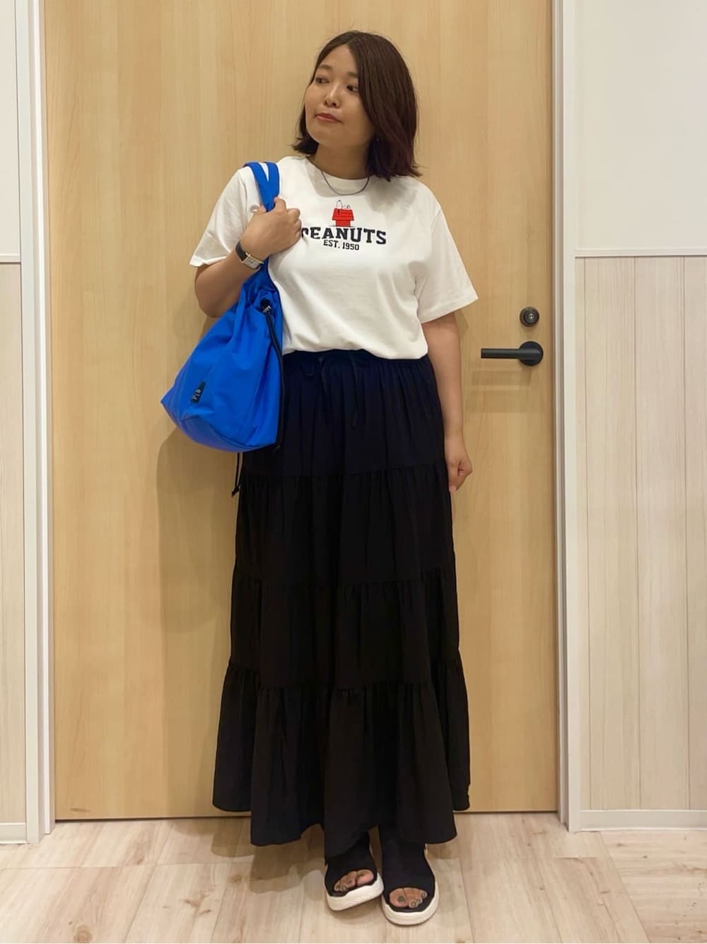 ホワイト系のTシャツ/カットソー、ブラック系のスカート、ブラック系のサンダルを着用したレディースの夏コーディネートの1枚目の写真