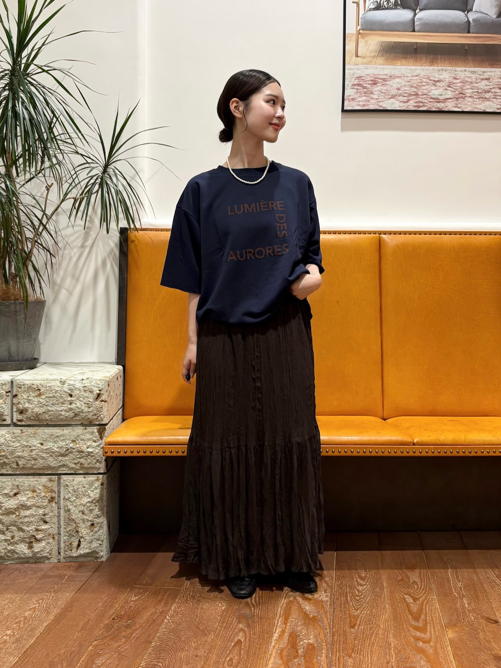 ブラウン系のスカート、ブルー系のTシャツ/カットソー、ゴールド系のネックレスを着用したレディースの秋コーディネートの1枚目の写真