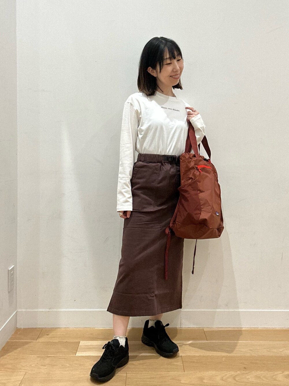 ブラウン系のスカート、グレー系のTシャツ/カットソー、ブラウン系のバックパック/リュックを着用したレディースの秋コーディネートの1枚目の写真