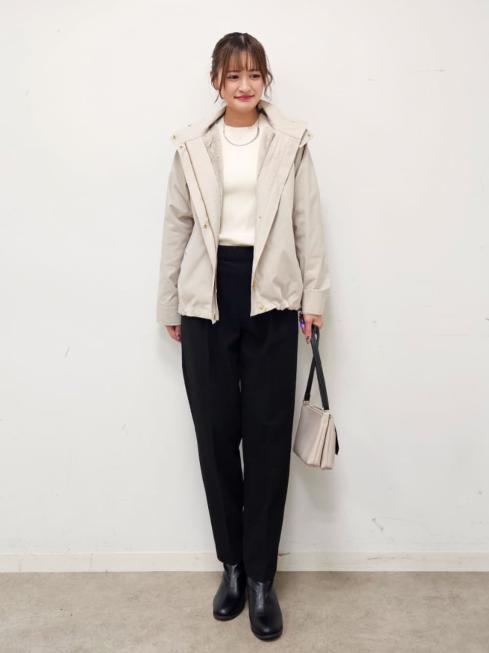 ブラック系のショルダーバッグ、ベージュ系のブルゾン、ホワイト系のニット/セーターを着用したレディースの冬コーディネートの1枚目の写真