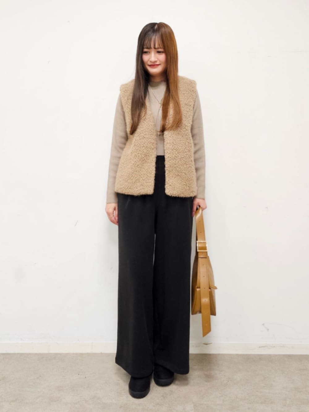 ブラック系のブーツ、ブラウン系のベスト、ベージュ系のニット/セーターを着用したレディースの秋コーディネートの1枚目の写真