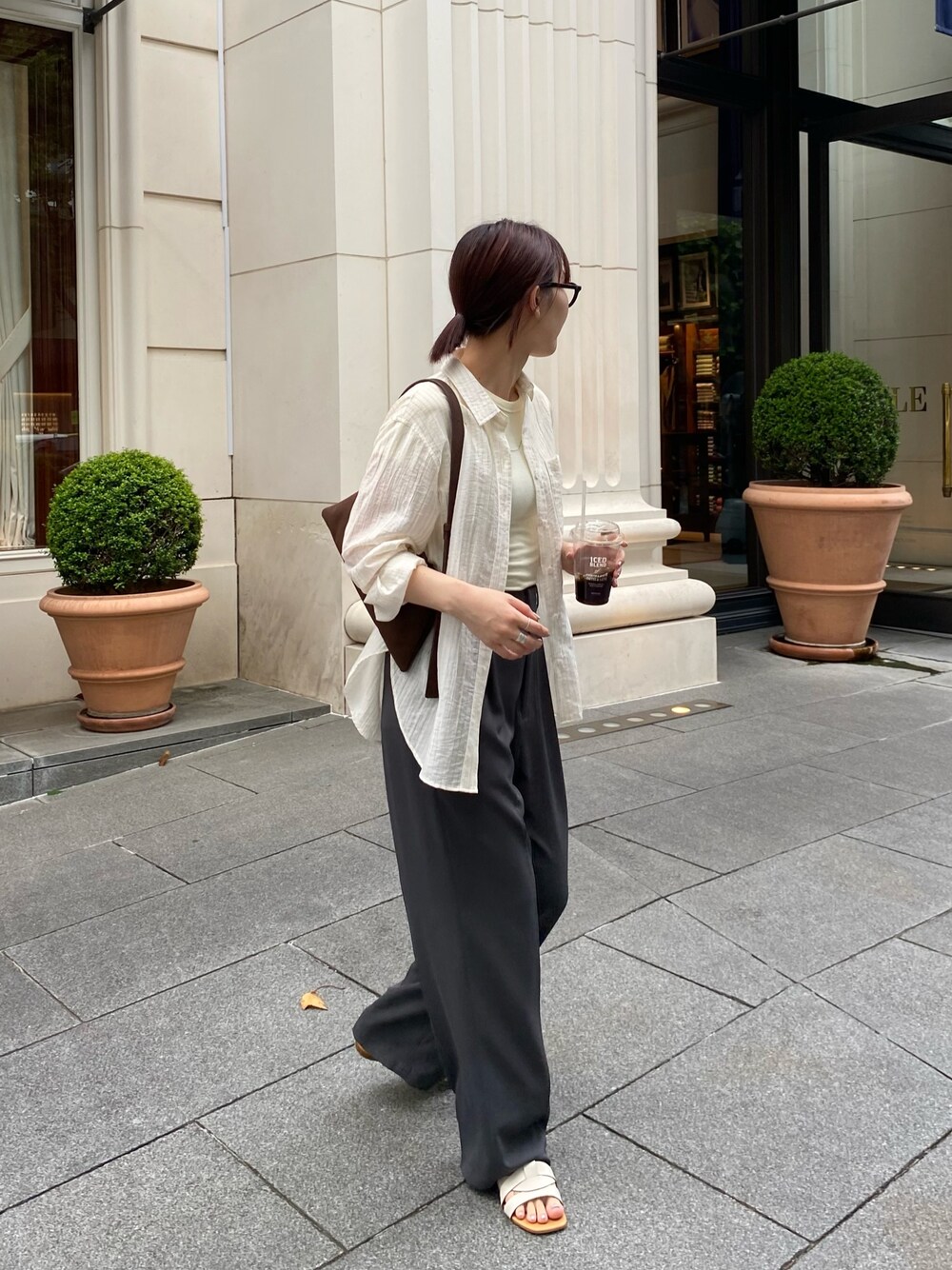 ブラック系のスラックス、ホワイト系のシャツ/ブラウス、ブラウン系のショルダーバッグを着用したレディースの夏コーディネートの1枚目の写真
