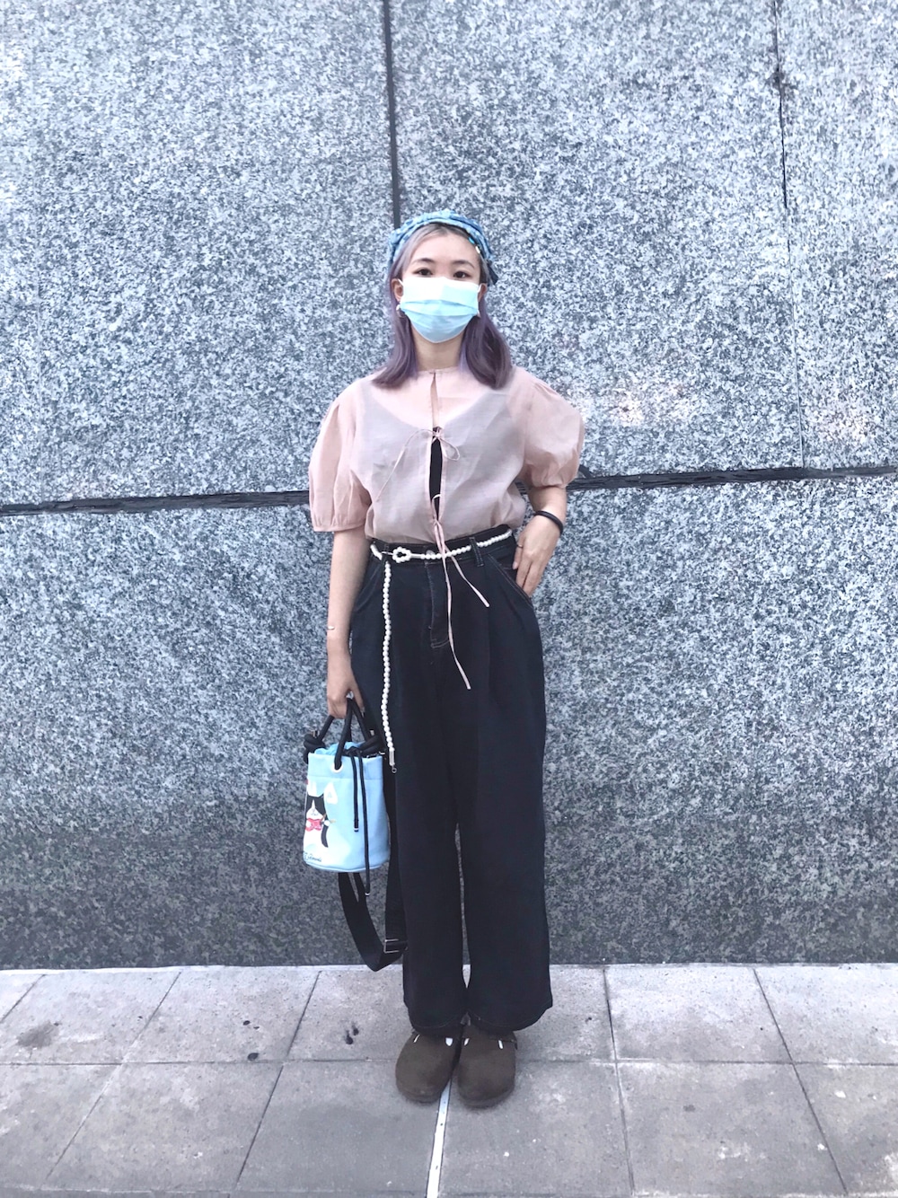 ピンク系のアンサンブル、ブルー系のクラッチバッグ、ブラック系のバングル/リストバンドを着用したレディースの秋コーディネートの1枚目の写真