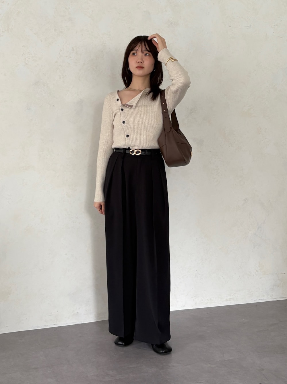 ブラック系のスラックス、ホワイト系のニット/セーター、ブラウン系のトートバッグを着用したレディースの秋コーディネートの1枚目の写真