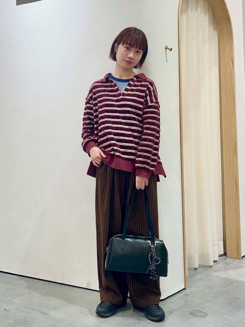 レッド系のTシャツ/カットソー、ブラウン系のスラックス、ブラック系のトートバッグを着用したレディースの冬コーディネートの1枚目の写真