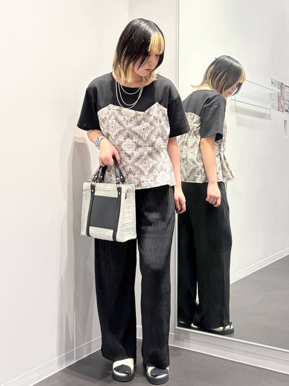 ホワイト系のショルダーバッグ、ホワイト系のサンダル、ブラック系のTシャツ/カットソーを着用したレディースの春コーディネートの1枚目の写真