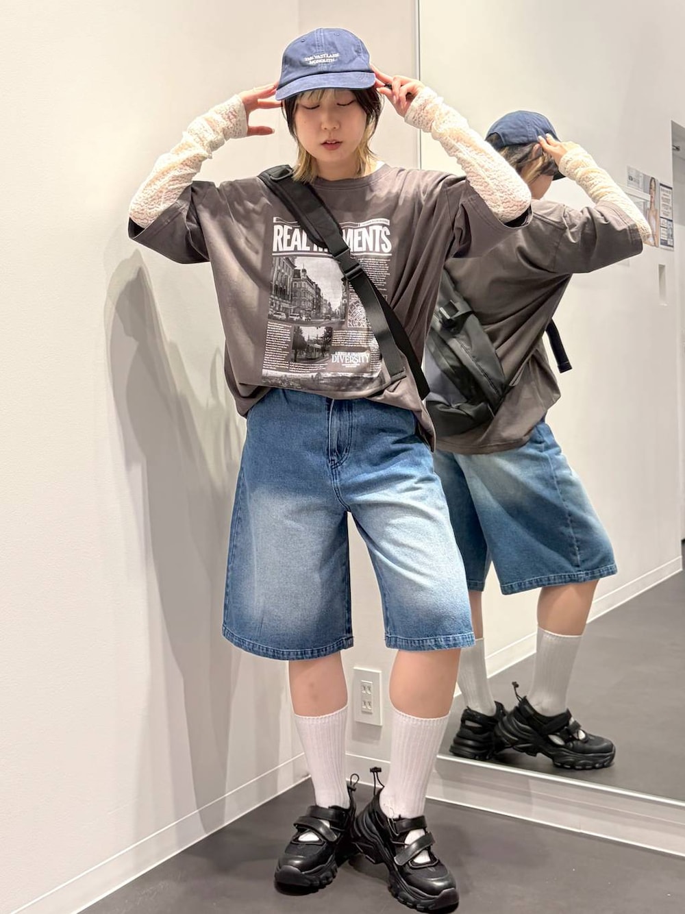 ブラック系のスニーカー、ブラック系のボディバッグ/ウエストポーチ、ホワイト系のTシャツ/カットソーを着用したレディースの春コーディネートの1枚目の写真