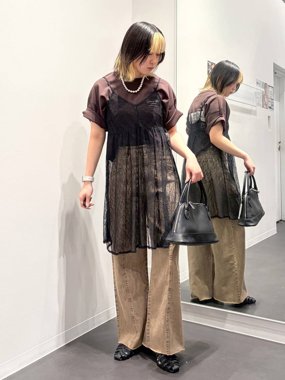 ブラック系のサンダル、ブラック系のハンドバッグ、ベージュ系のデニムパンツを着用したレディースの春コーディネートの1枚目の写真