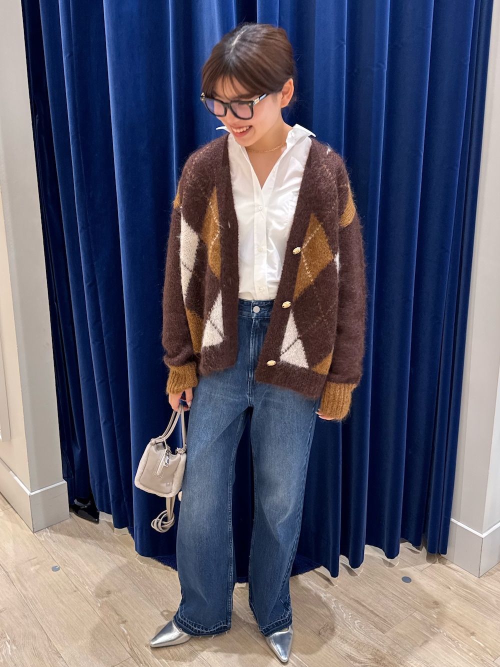 ブラウン系のカーディガン/ボレロ、ホワイト系のシャツ/ブラウス、ブルー系のデニムパンツを着用したレディースの秋コーディネートの1枚目の写真