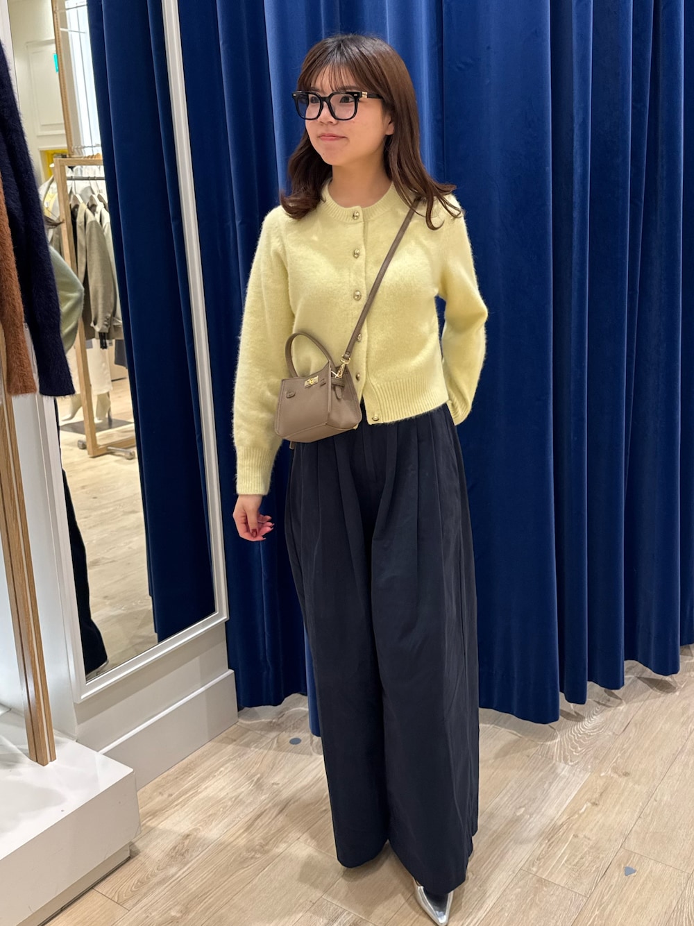 イエロー系のカーディガン/ボレロ、ブルー系のその他パンツ、ベージュ系のショルダーバッグを着用したレディースの秋コーディネートの1枚目の写真
