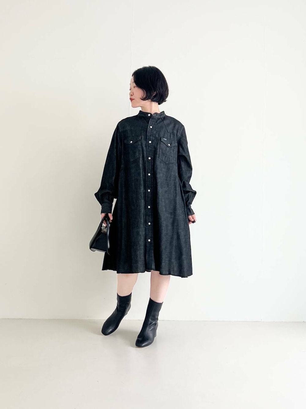 ブラック系のワンピース、ブラック系のハンドバッグを着用したレディースの夏コーディネートの1枚目の写真