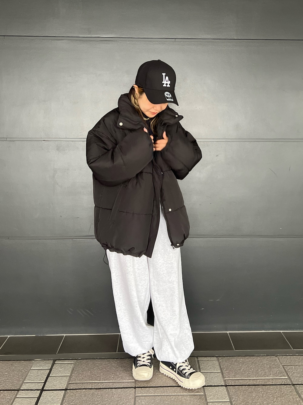 ブラック系のスニーカー、ベージュ系のスウェットパンツ、ブラック系のダウンジャケット/コートを着用したレディースの冬コーディネートの1枚目の写真