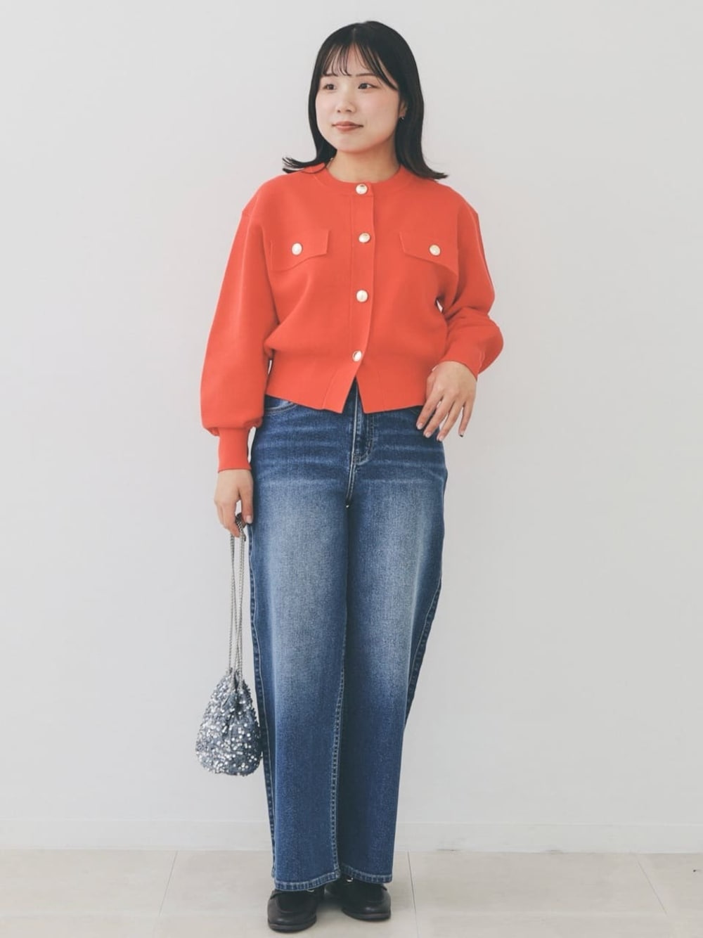オレンジ系のカーディガン/ボレロ、ブルー系のデニムパンツ、グレー系のショルダーバッグを着用したレディースの冬コーディネートの1枚目の写真