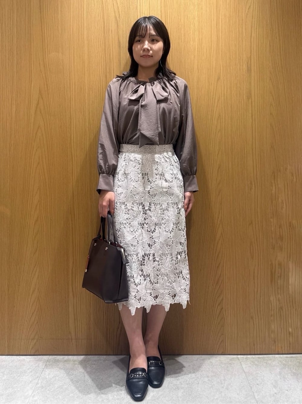 ブラウン系のシャツ/ブラウス、ベージュ系のスカート、ブラウン系のトートバッグを着用したレディースの秋コーディネートの1枚目の写真