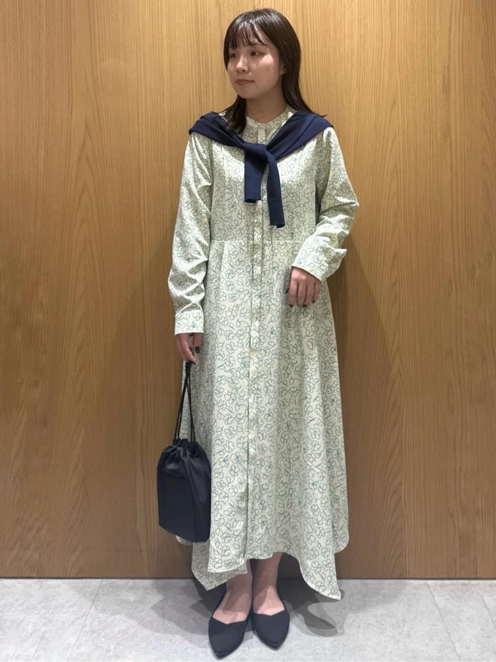 ベージュ系のワンピース、ブルー系のカーディガン/ボレロ、ブラック系のショルダーバッグを着用したレディースの春コーディネートの1枚目の写真
