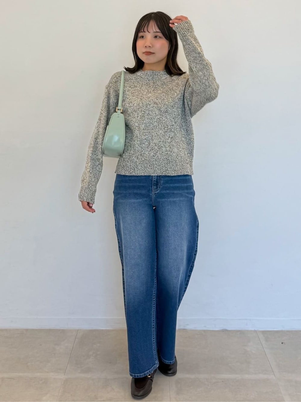 イエロー系のニット/セーター、ブルー系のデニムパンツ、グリーン系のショルダーバッグを着用したレディースの春コーディネートの1枚目の写真