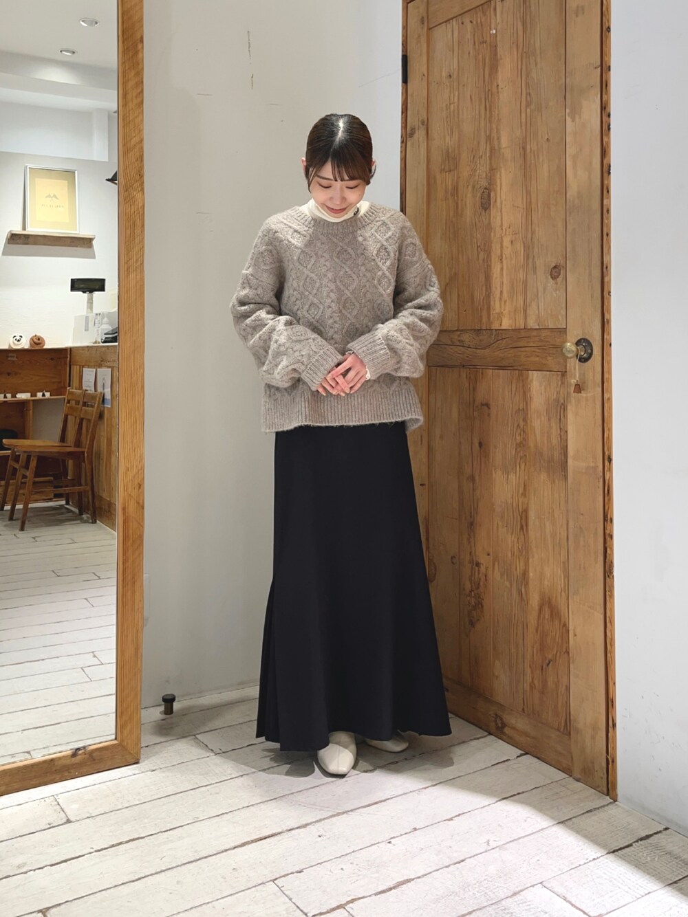 ブラック系のスカート、ホワイト系のTシャツ/カットソー、ベージュ系のニット/セーターを着用したレディースの冬コーディネートの1枚目の写真