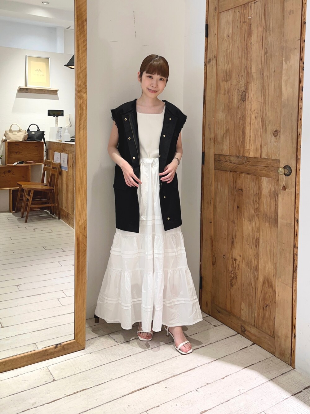 ホワイト系のタンクトップ、ホワイト系のスカート、ブラック系のミリタリージャケットを着用したレディースの夏コーディネートの1枚目の写真