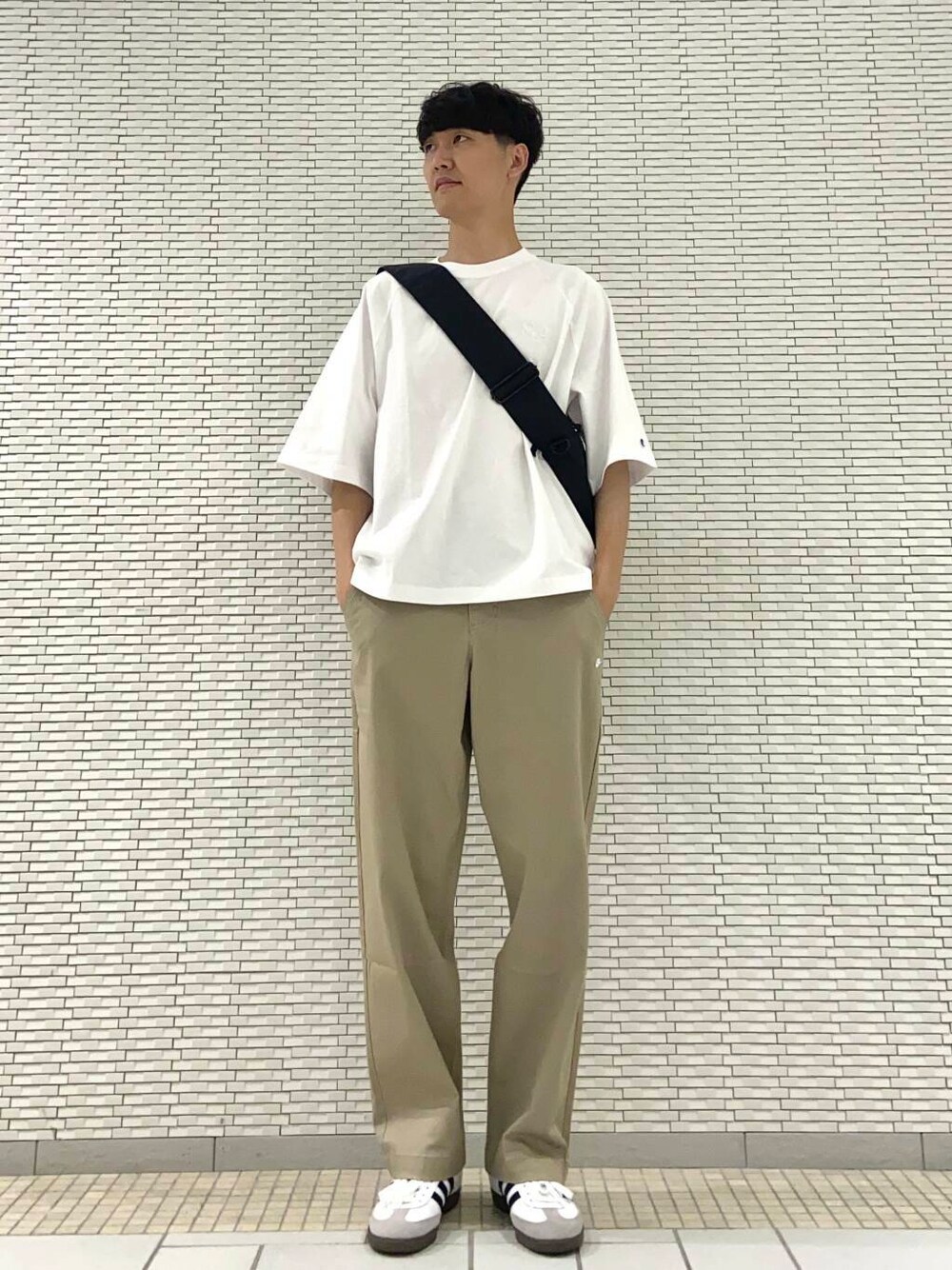 ホワイト系のTシャツ/カットソー、ブラック系のショルダーバッグ、ホワイト系のスニーカーを着用したメンズの夏コーディネートの1枚目の写真