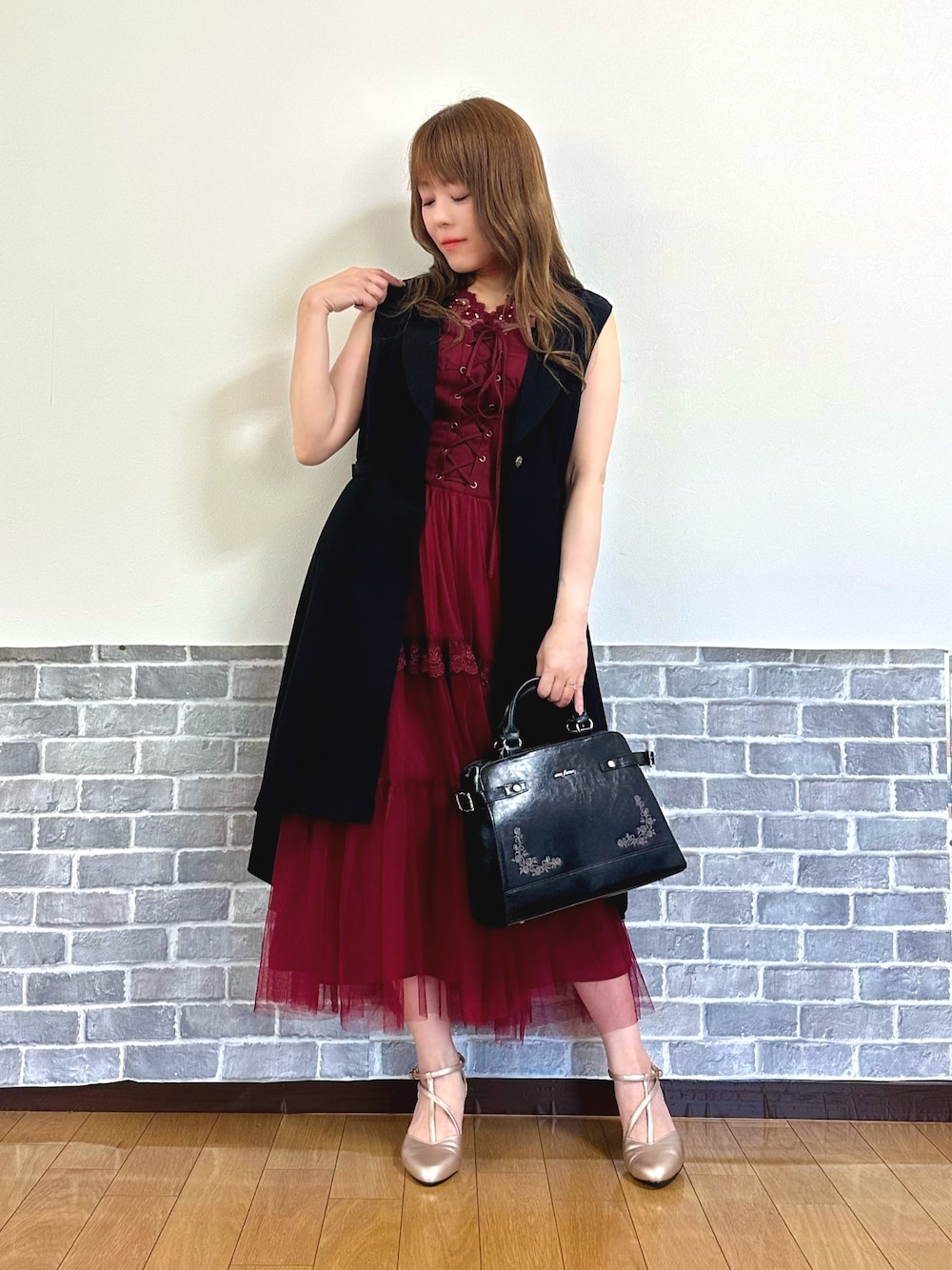 レッド系のタンクトップ、レッド系のジャンパースカート、ブラック系のベストを着用したレディースの夏コーディネートの1枚目の写真