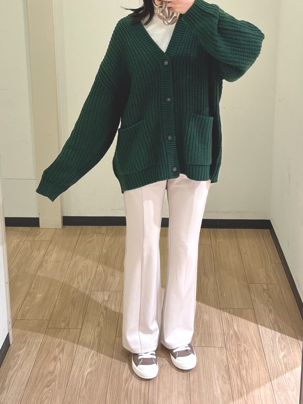 グリーン系のカーディガン/ボレロ、ホワイト系のトップス、ホワイト系のスラックスを着用したレディースの冬コーディネートの1枚目の写真