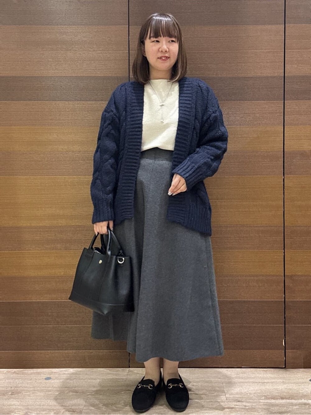 ブルー系のカーディガン/ボレロ、ホワイト系のニット/セーター、グレー系のスカートを着用したレディースの冬コーディネートの1枚目の写真