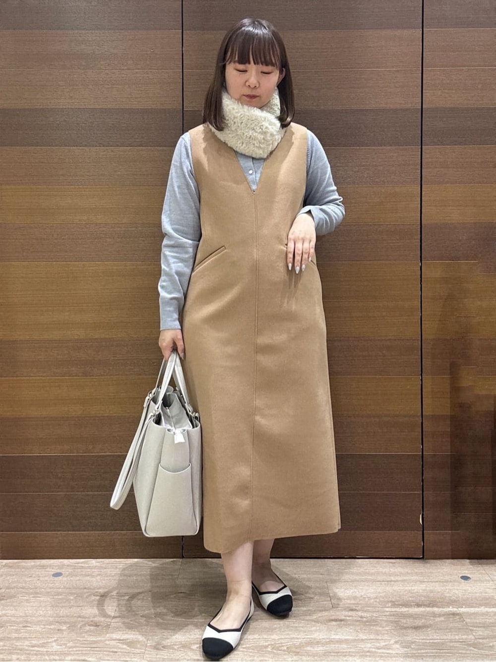 グレー系のカーディガン/ボレロ、イエロー系のワンピース、ベージュ系のトートバッグを着用したレディースの冬コーディネートの1枚目の写真
