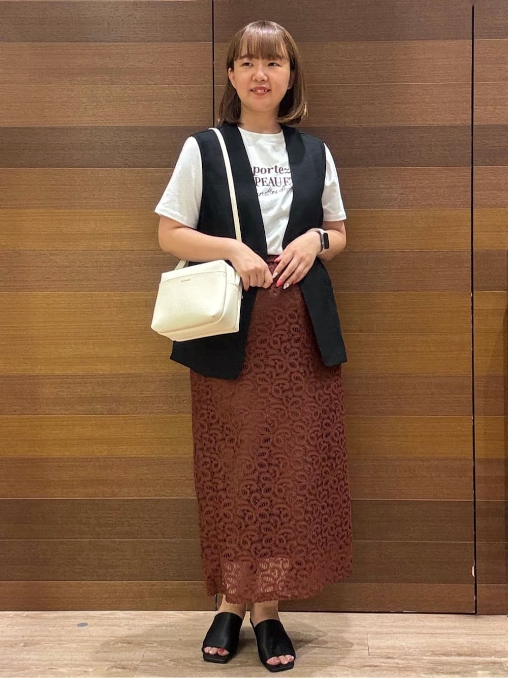 ブラック系のベスト、ホワイト系のTシャツ/カットソー、ブラウン系のスカートを着用したレディースの夏コーディネートの1枚目の写真