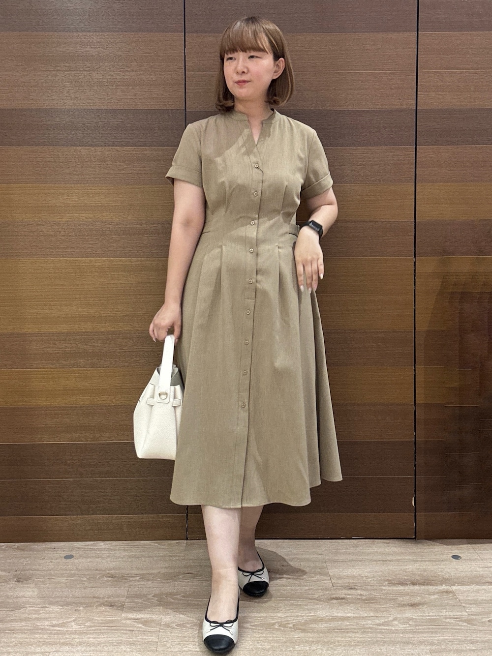 イエロー系のワンピース、ホワイト系のトートバッグ、ベージュ系のパンプスを着用したレディースの夏コーディネートの1枚目の写真