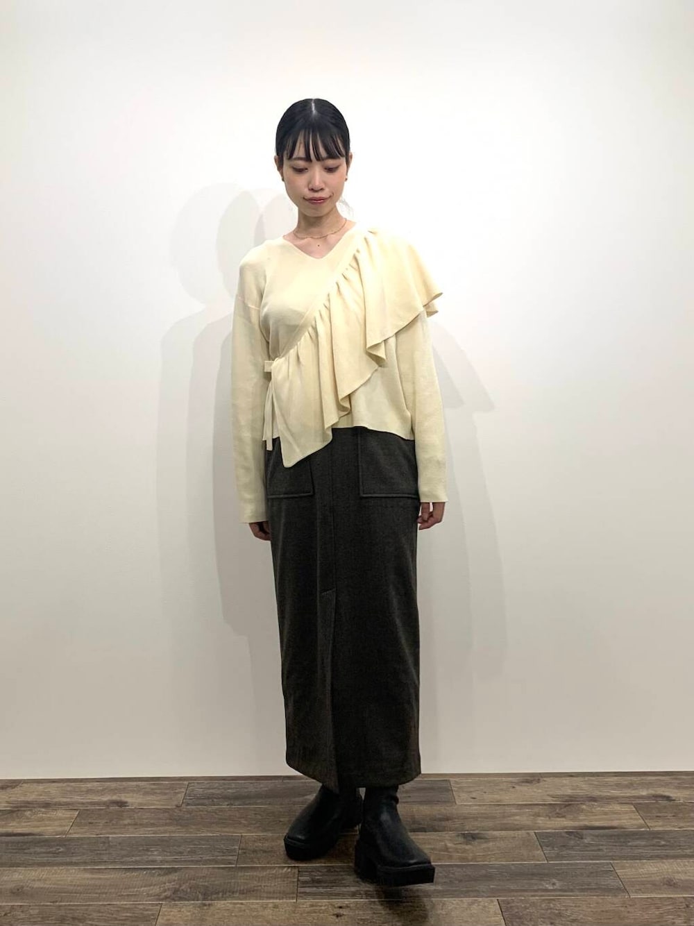 ブラック系のブーツ、ホワイト系のニット/セーター、ブラウン系のスカートを着用したレディースの秋コーディネートの1枚目の写真