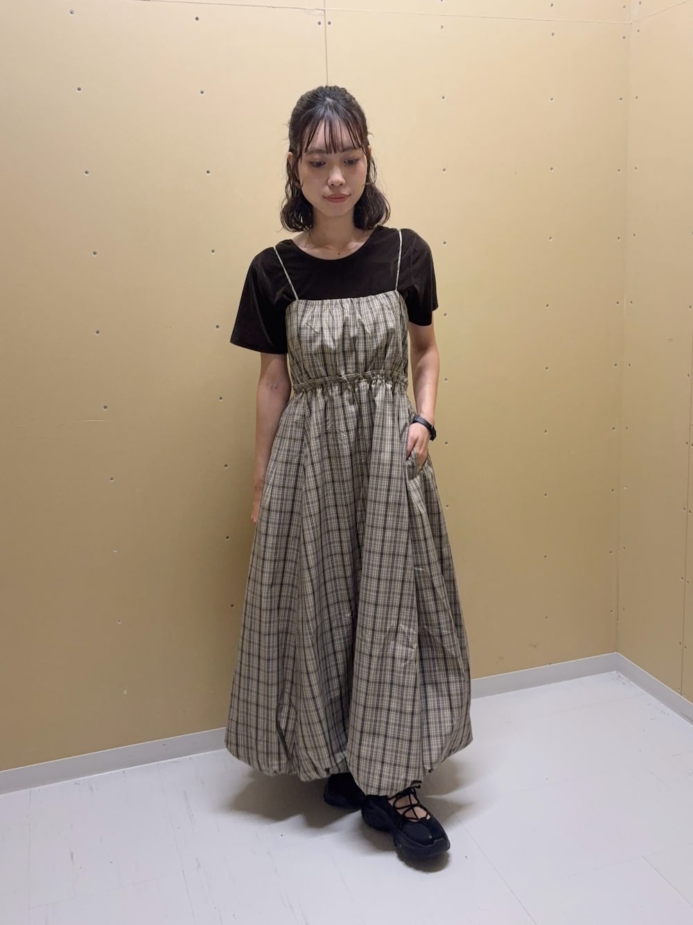 ベージュ系のワンピース、ブラウン系のTシャツ/カットソー、ブラック系のスニーカーを着用したレディースの夏コーディネートの1枚目の写真