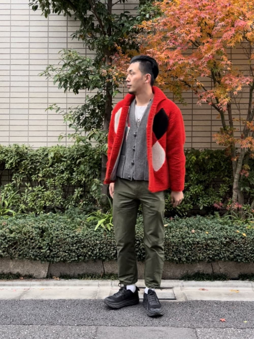 ブラック系のスニーカー、グリーン系のチノパンツ、レッド系のその他アウターを着用したメンズの冬コーディネートの1枚目の写真