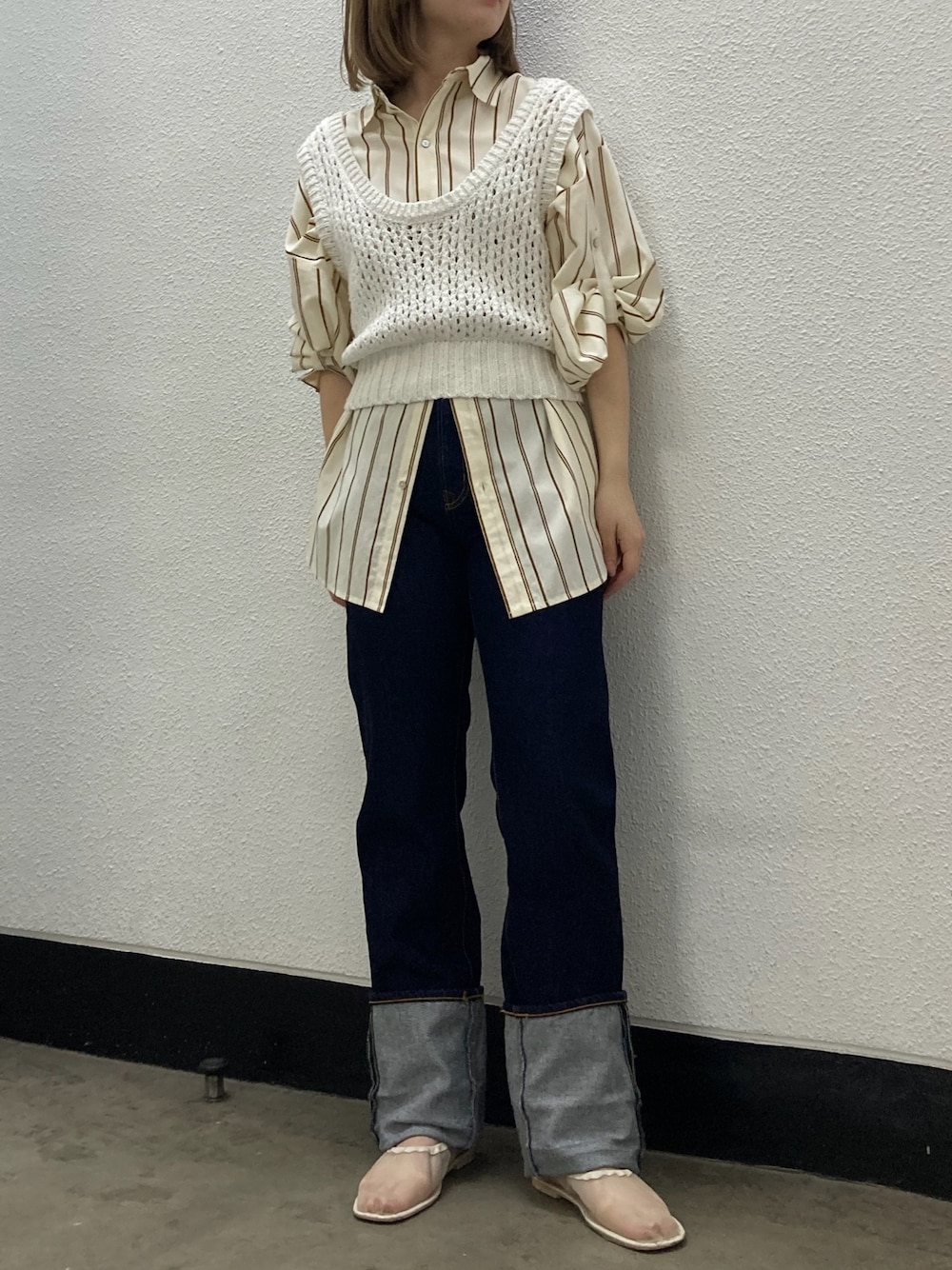 イエロー系のシャツ/ブラウス、ホワイト系のベスト、ブルー系のデニムパンツを着用したレディースの冬コーディネートの1枚目の写真