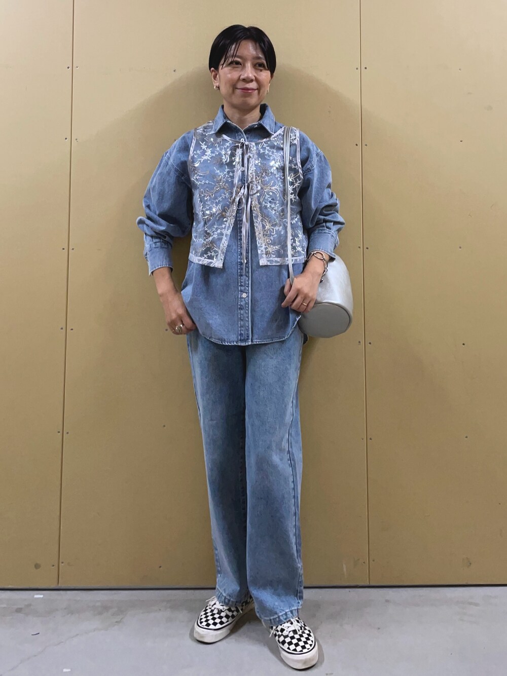 シルバー系のベスト、ブルー系のシャツ/ブラウス、シルバー系のショルダーバッグを着用したレディースの夏コーディネートの1枚目の写真