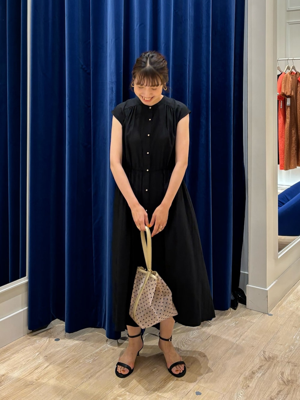 ブラック系のワンピース、ベージュ系のトートバッグ、ブラック系のサンダルを着用したレディースの春コーディネートの1枚目の写真