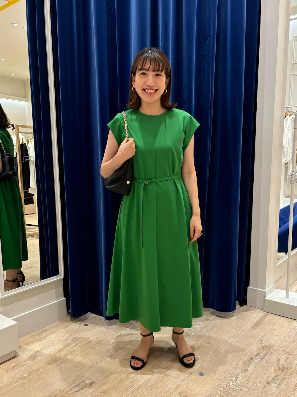 グリーン系のワンピース、ブラック系のショルダーバッグ、ブラック系のサンダルを着用したレディースの夏コーディネートの1枚目の写真