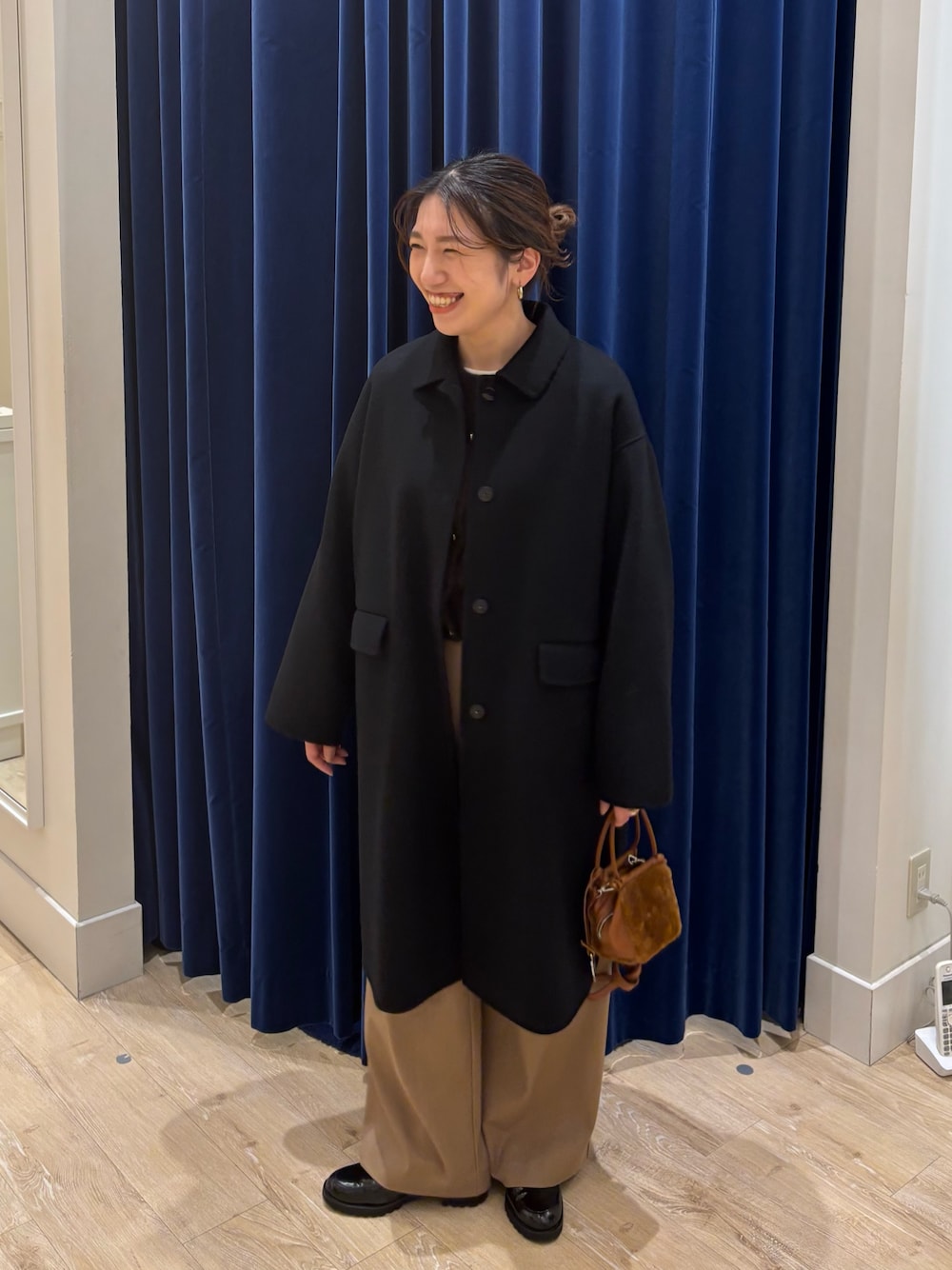 ブラック系のステンカラーコート、ブラウン系のカーディガン/ボレロ、イエロー系のその他パンツを着用したレディースの秋コーディネートの1枚目の写真