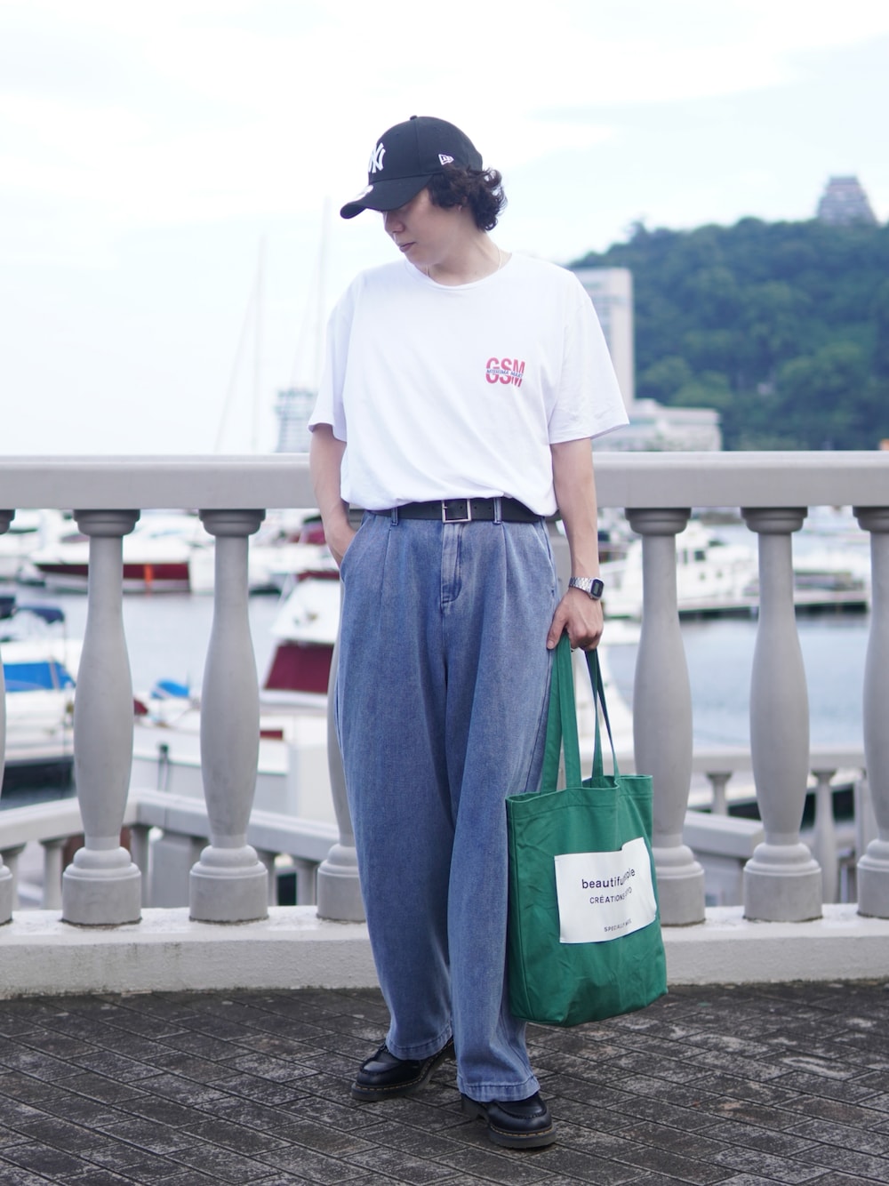 ホワイト系のTシャツ/カットソー、グリーン系のトートバッグ、ブルー系のデニムパンツを着用したメンズの夏コーディネートの1枚目の写真