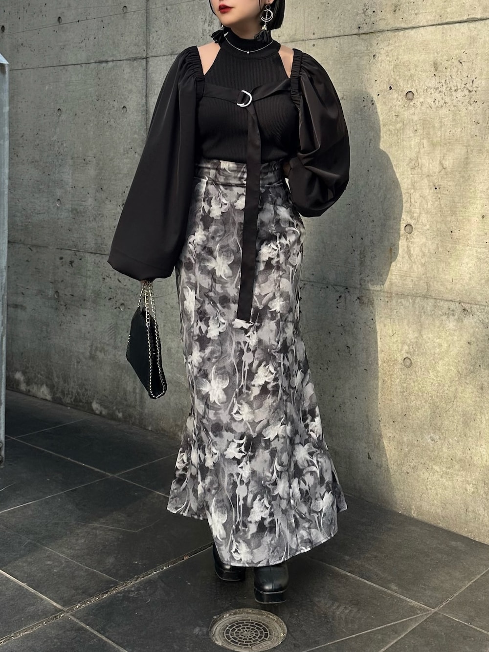 グレー系のスカート、ブラック系のカーディガン/ボレロ、ブラック系のキャミソールを着用したレディースの春コーディネートの1枚目の写真