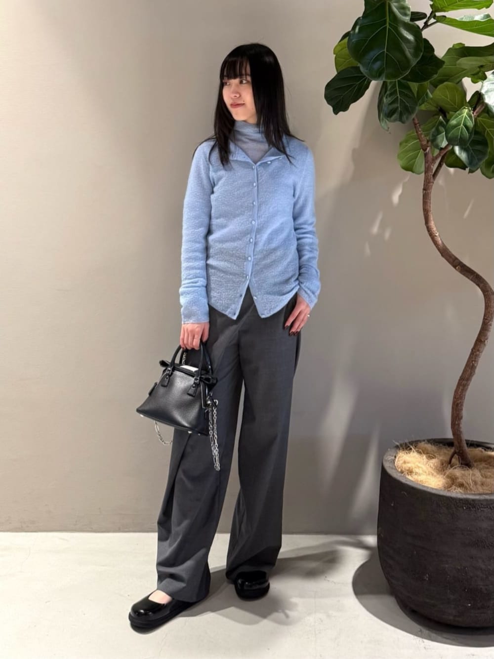 グレー系のスラックス、ブルー系のカーディガン/ボレロ、ブルー系のニット/セーターを着用したレディースの秋コーディネートの1枚目の写真