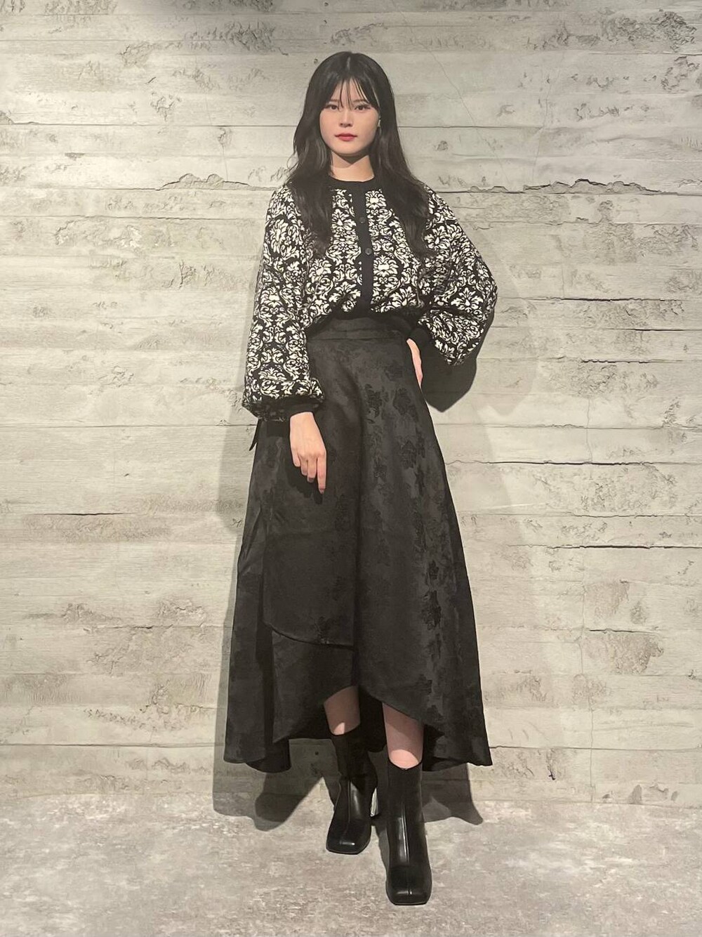 ブラック系のブーツ、ブラック系のニット/セーター、ブラック系のスカートを着用したレディースの秋コーディネートの1枚目の写真