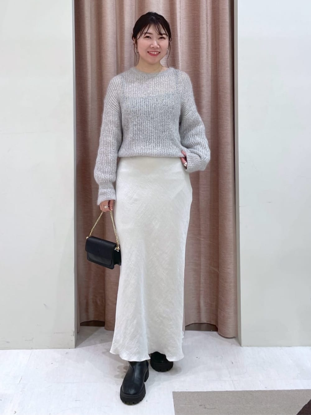 グレー系のスカート、シルバー系のニット/セーターを着用したレディースの秋コーディネートの1枚目の写真