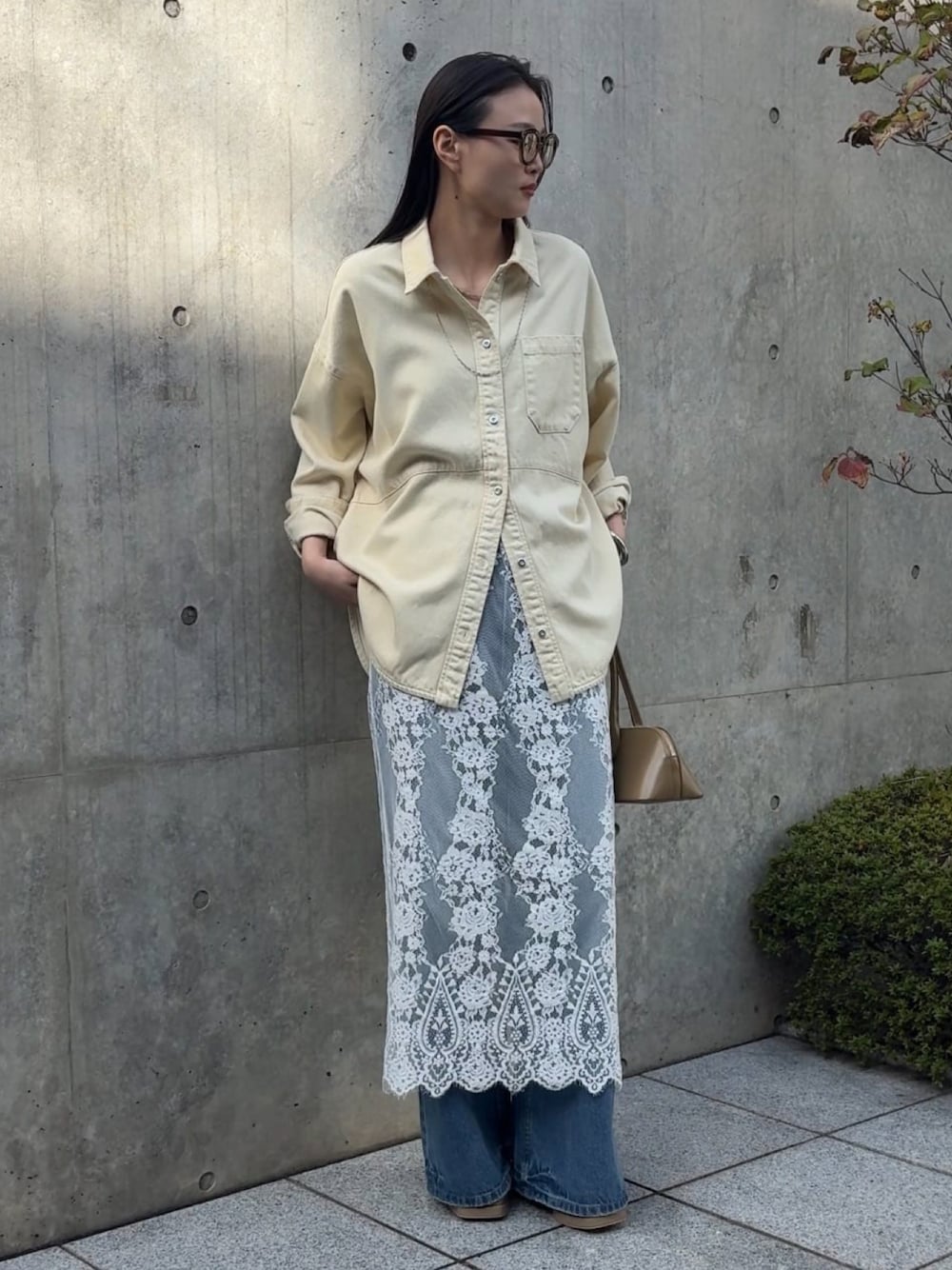 イエロー系のトップス、ホワイト系のスカート、ブルー系のデニムパンツを着用したレディースの冬コーディネートの1枚目の写真