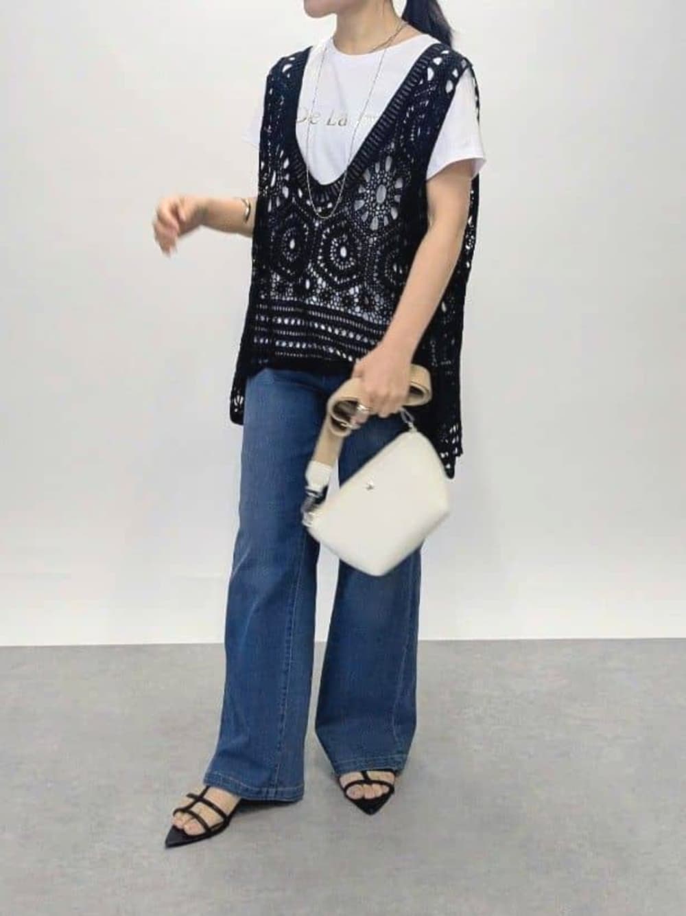 ブルー系のデニムパンツ、ブラック系のサンダル、ブラック系のベストを着用したレディースの夏コーディネートの1枚目の写真