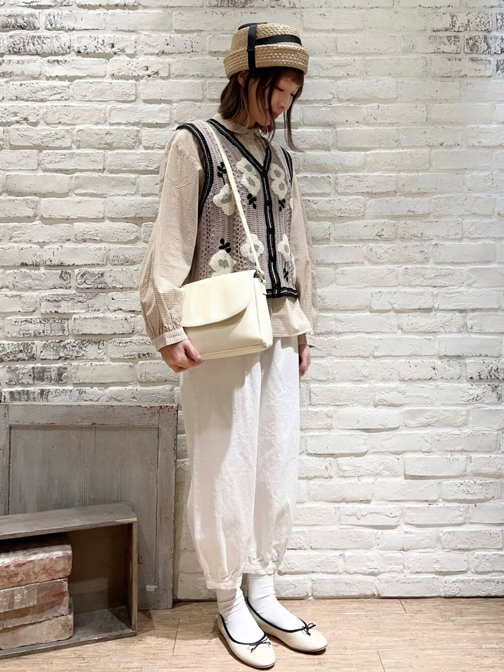 ベージュ系のシャツ/ブラウス、ベージュ系のベスト、ホワイト系のハンドバッグを着用したレディースの春コーディネートの1枚目の写真