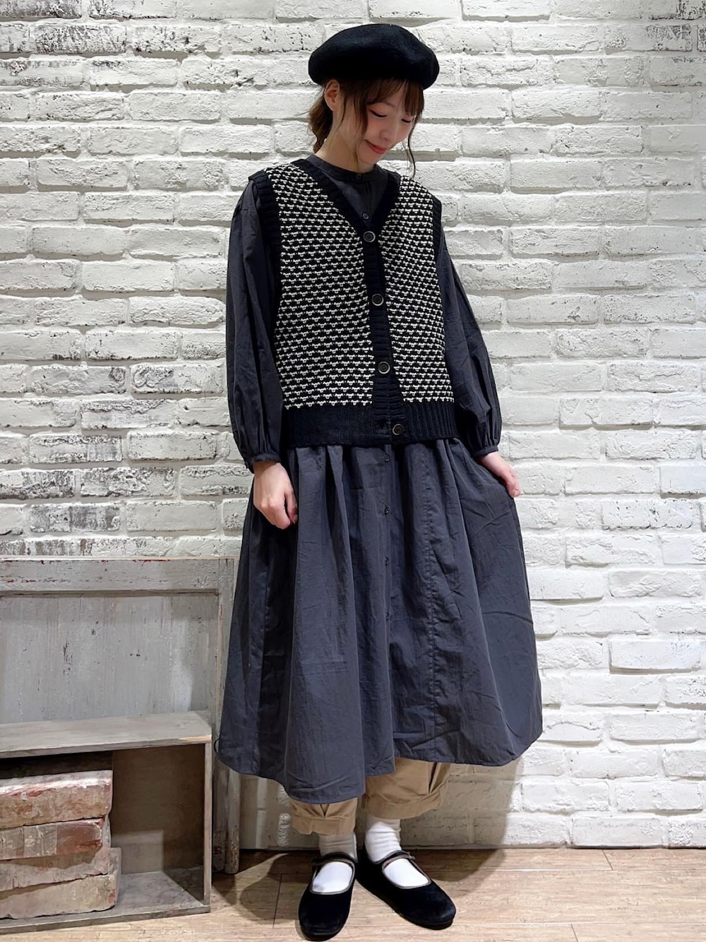 ブラック系のベスト、グレー系のワンピース、ベージュ系のその他パンツを着用したレディースの秋コーディネートの1枚目の写真