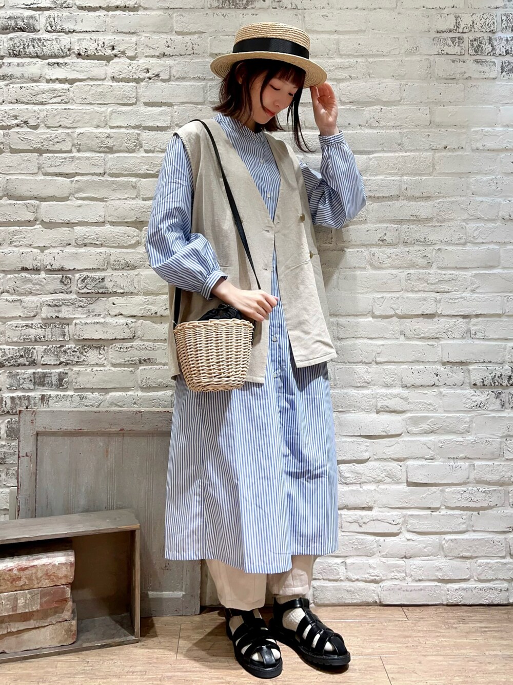 ホワイト系のベスト、ブラック系のハンドバッグ、ブルー系のシャツワンピースを着用したレディースの春コーディネートの1枚目の写真