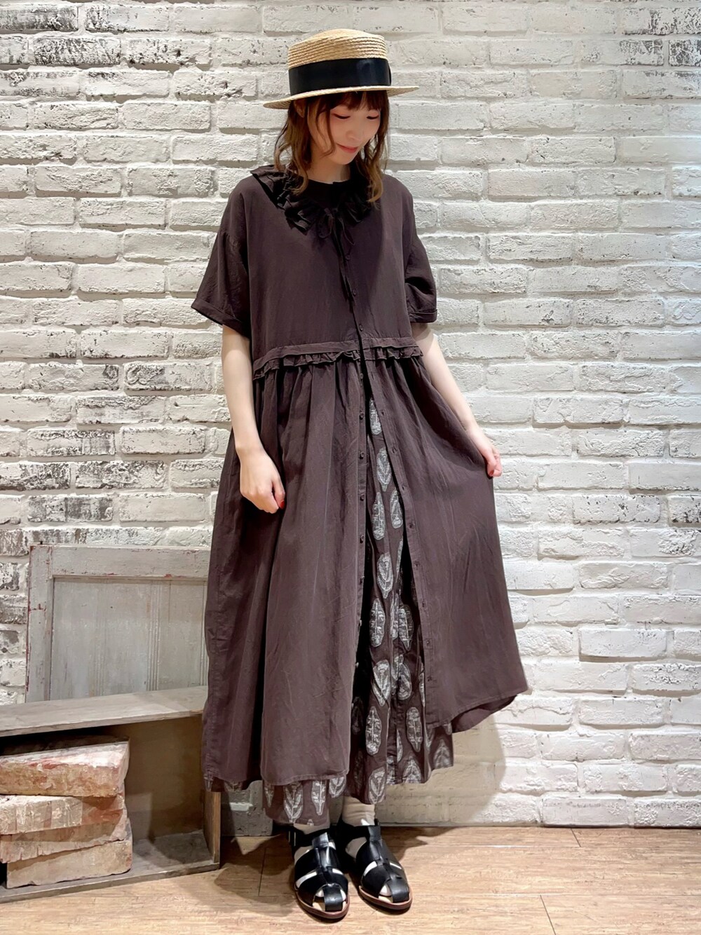 グレー系のワンピース、ブラウン系のスカート、ブラック系のサンダルを着用したレディースの春コーディネートの1枚目の写真