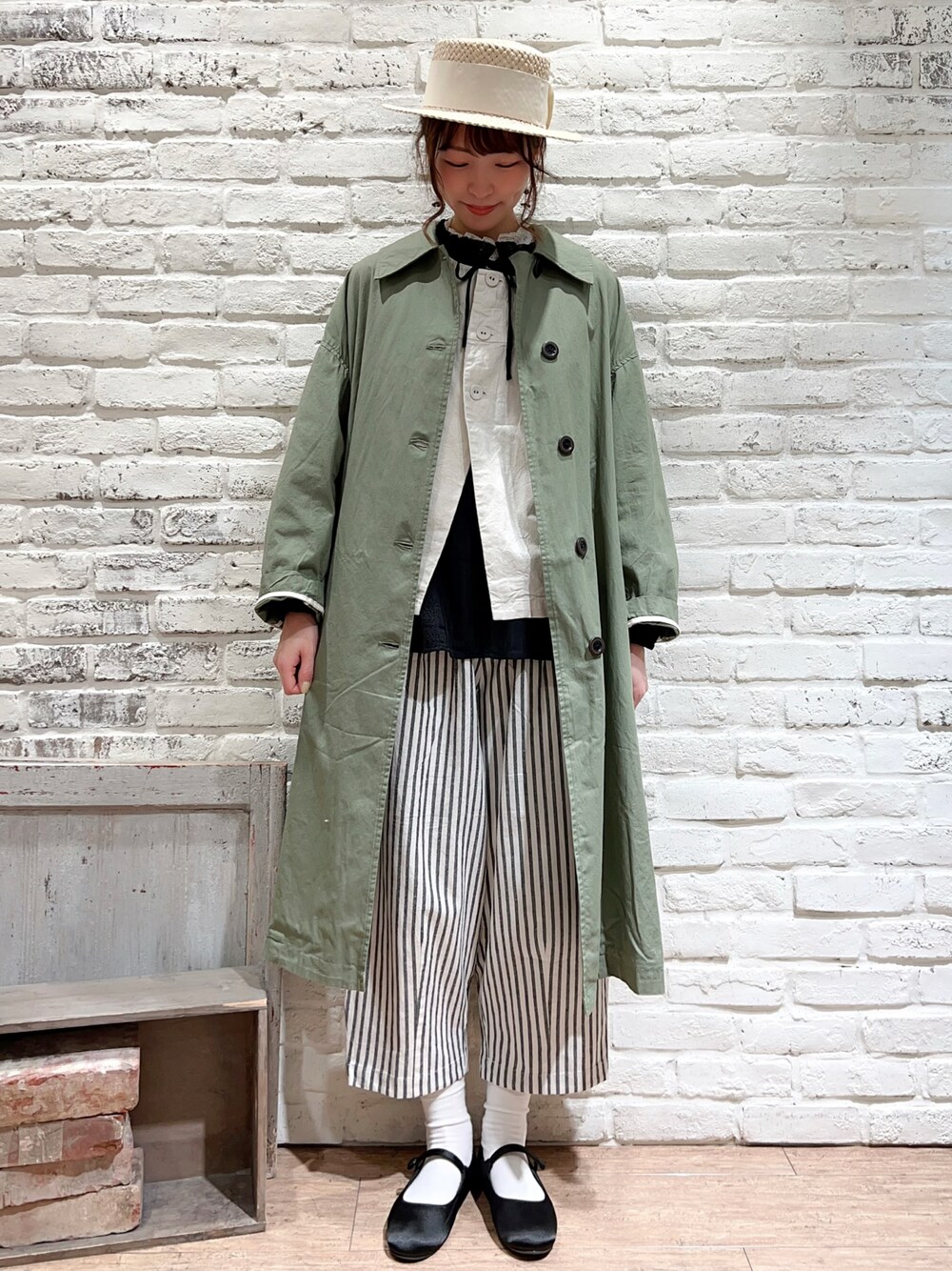 グリーン系のステンカラーコート、ホワイト系のベスト、ブラック系のシャツ/ブラウスを着用したレディースの春コーディネートの1枚目の写真