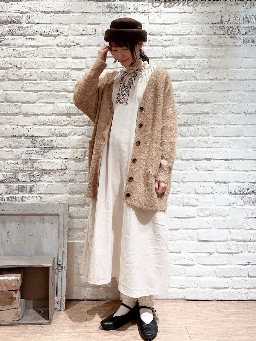 ホワイト系のニット/セーター、ホワイト系のワンピース、ベージュ系のカーディガン/ボレロを着用したレディースの冬コーディネートの1枚目の写真
